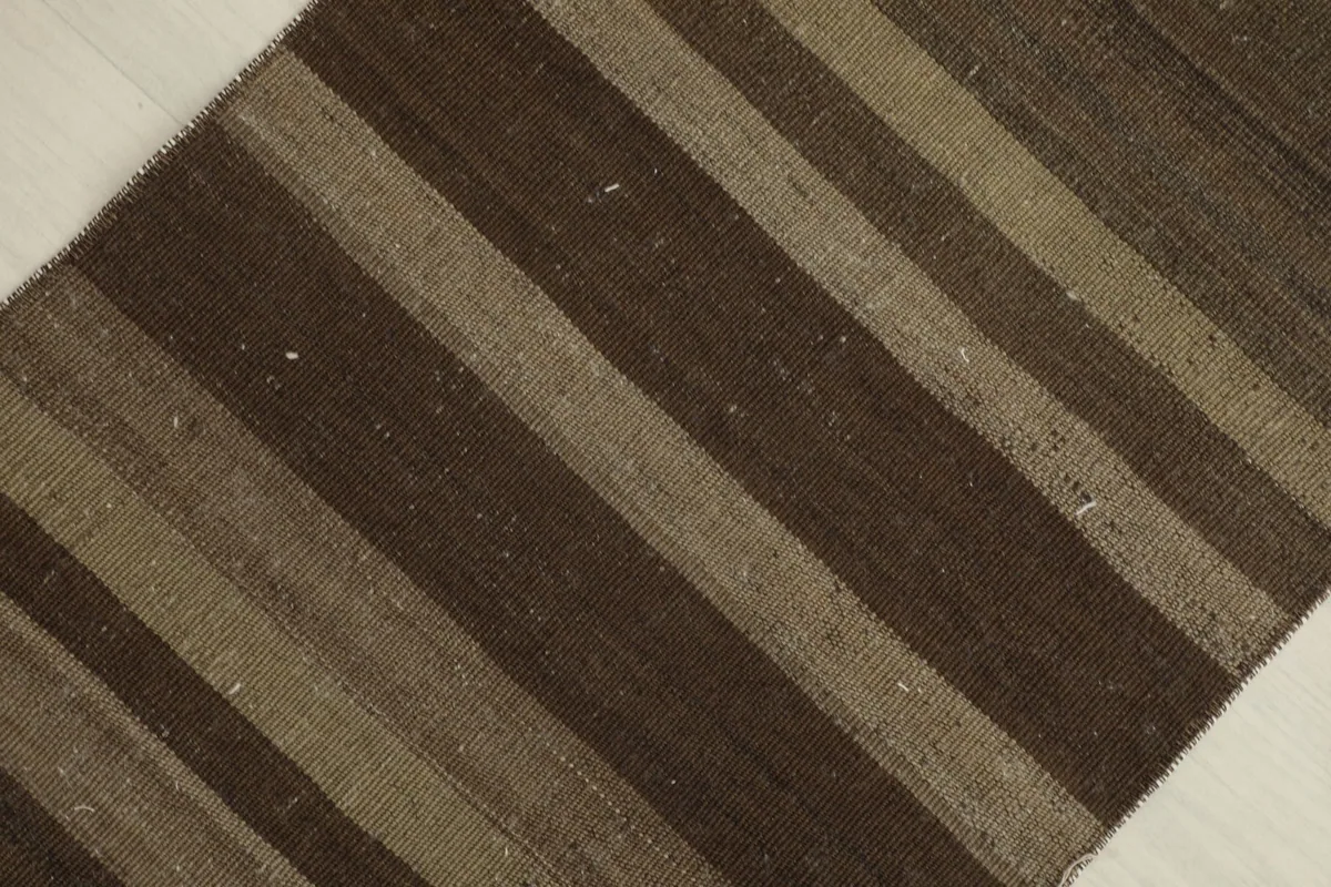 Overhead view focusing on the rich brown and tan stripes and wool texture of the area rug.