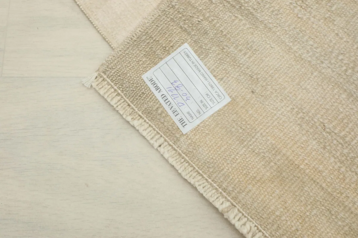 Close-up of the back of the rug with a label, illustrating the tight hand-knotted cotton foundation.