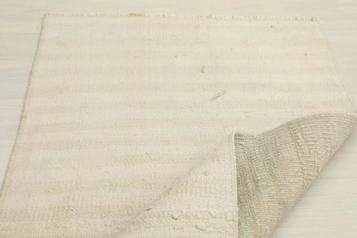 The rug with a corner gently lifted, showing the thickness and the back of the hand-knotted construction.