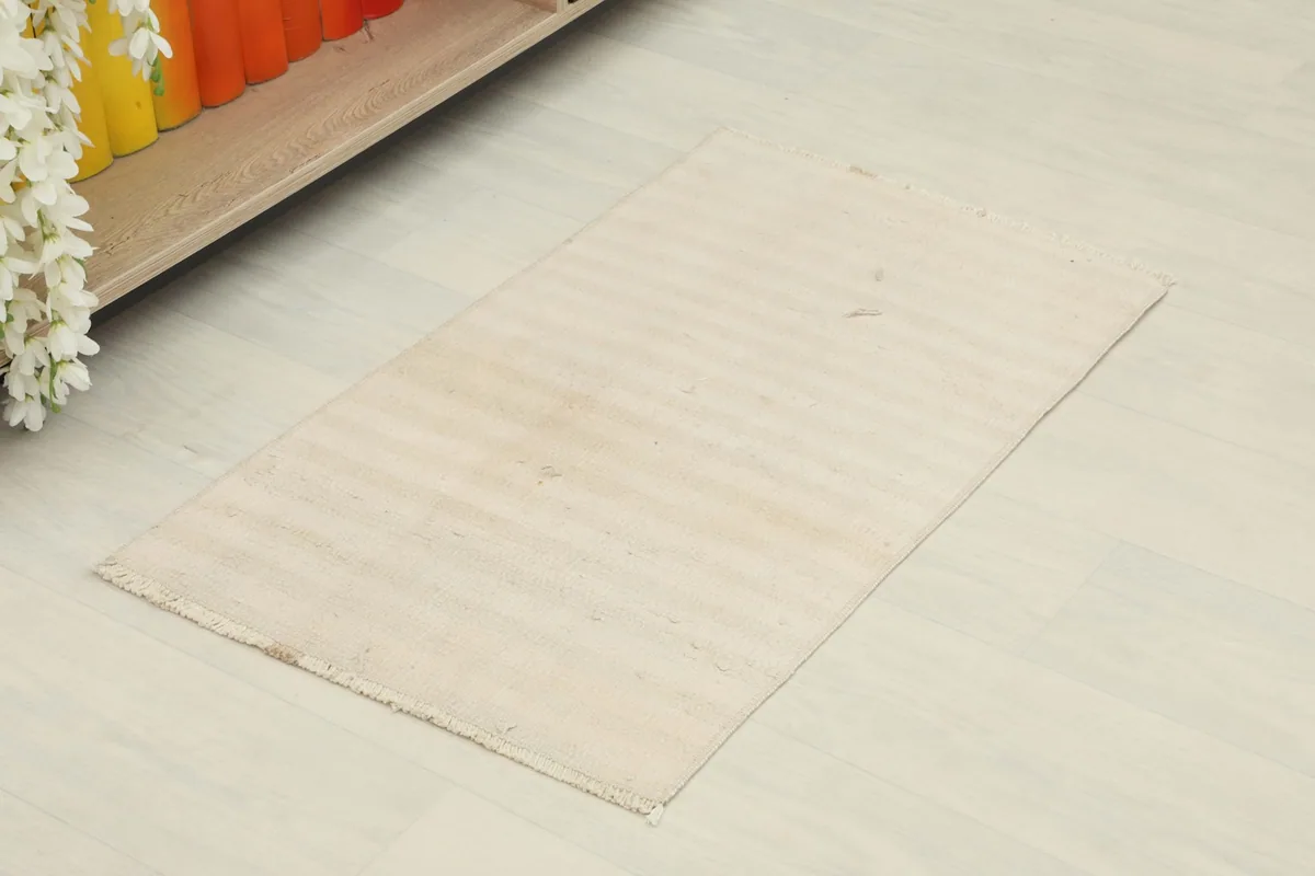 Overhead view of the ivory and beige vintage rug, showing its rectangular shape and subtle color variations.