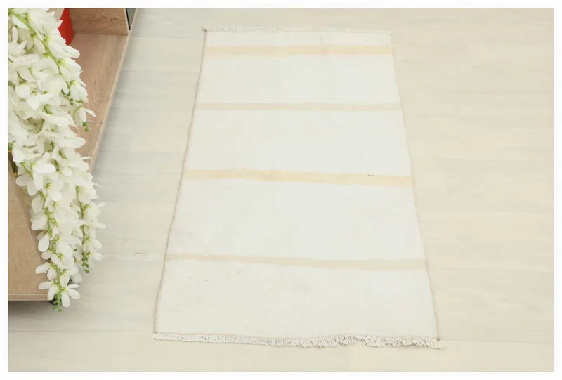 Full overhead view of the 1'9" x 3'5" cream and tan striped vintage Anatolian rug on a white floor.