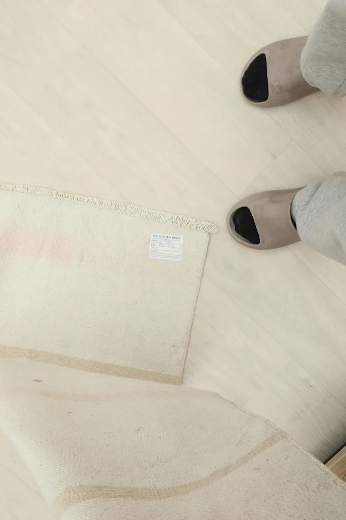 Overhead view with feet for scale next to the folded rug, showing the back label and overall size.