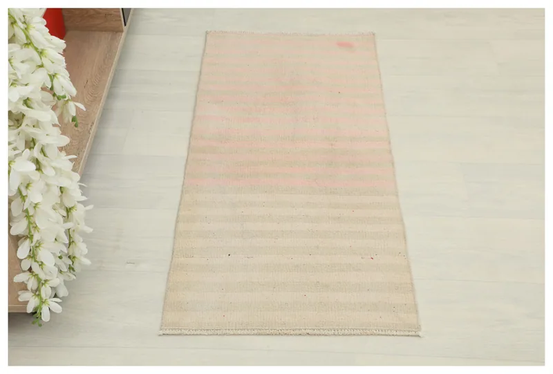 Full top view of the beige and pink striped vintage Anatolian doormat on a white background.