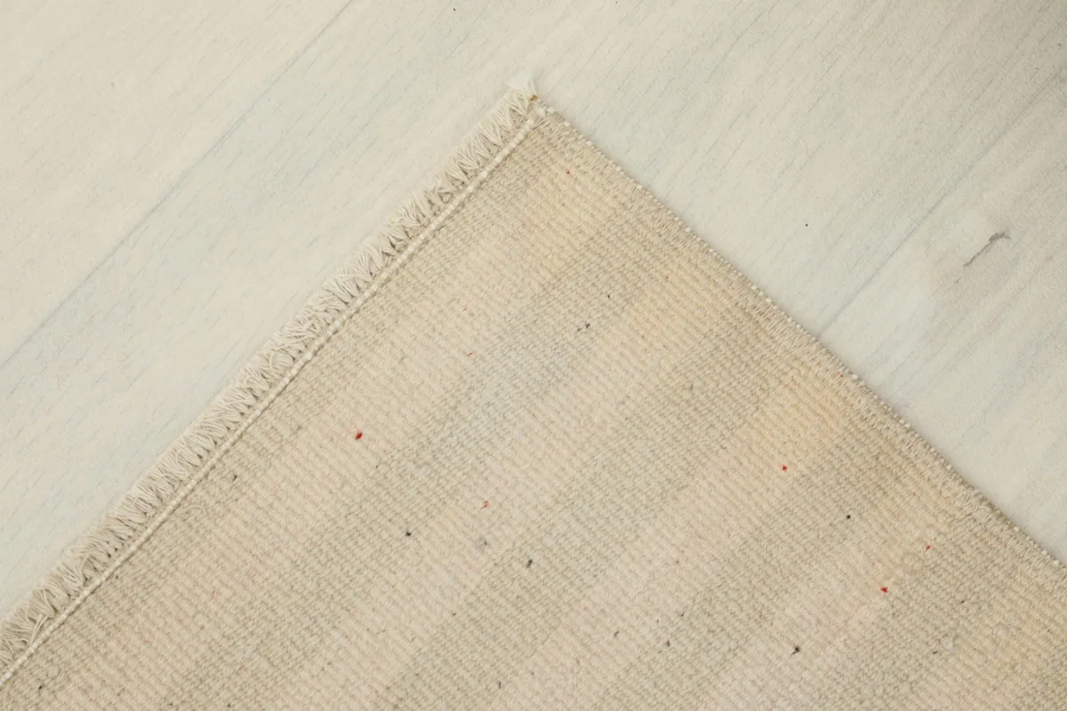 Corner view of the rug's reverse side, revealing the cotton foundation and hand-knotted construction.