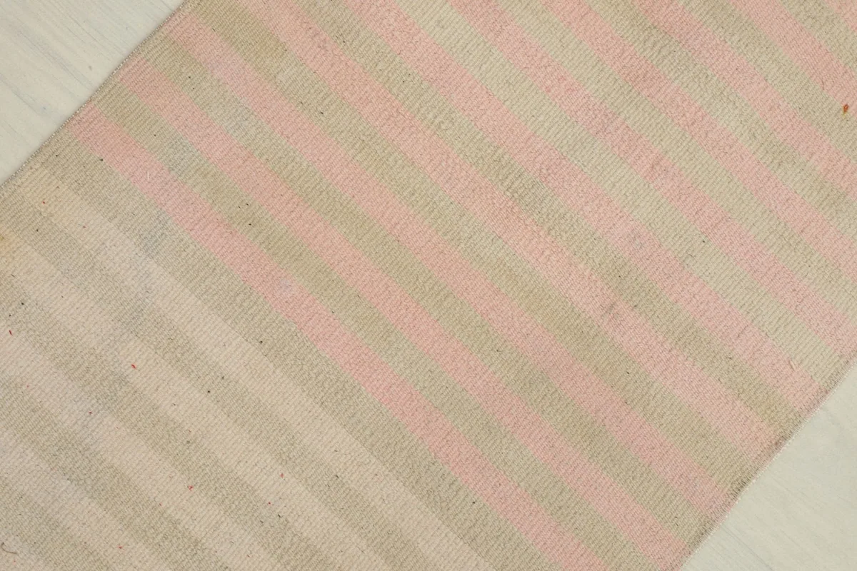 Overhead view showing the subtle pink and beige stripes running across the vintage rug.