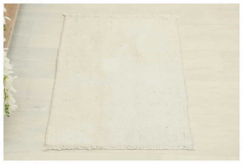 Full top view of the 1'7" x 2'3" ivory vintage Anatolian wool rug on a white background