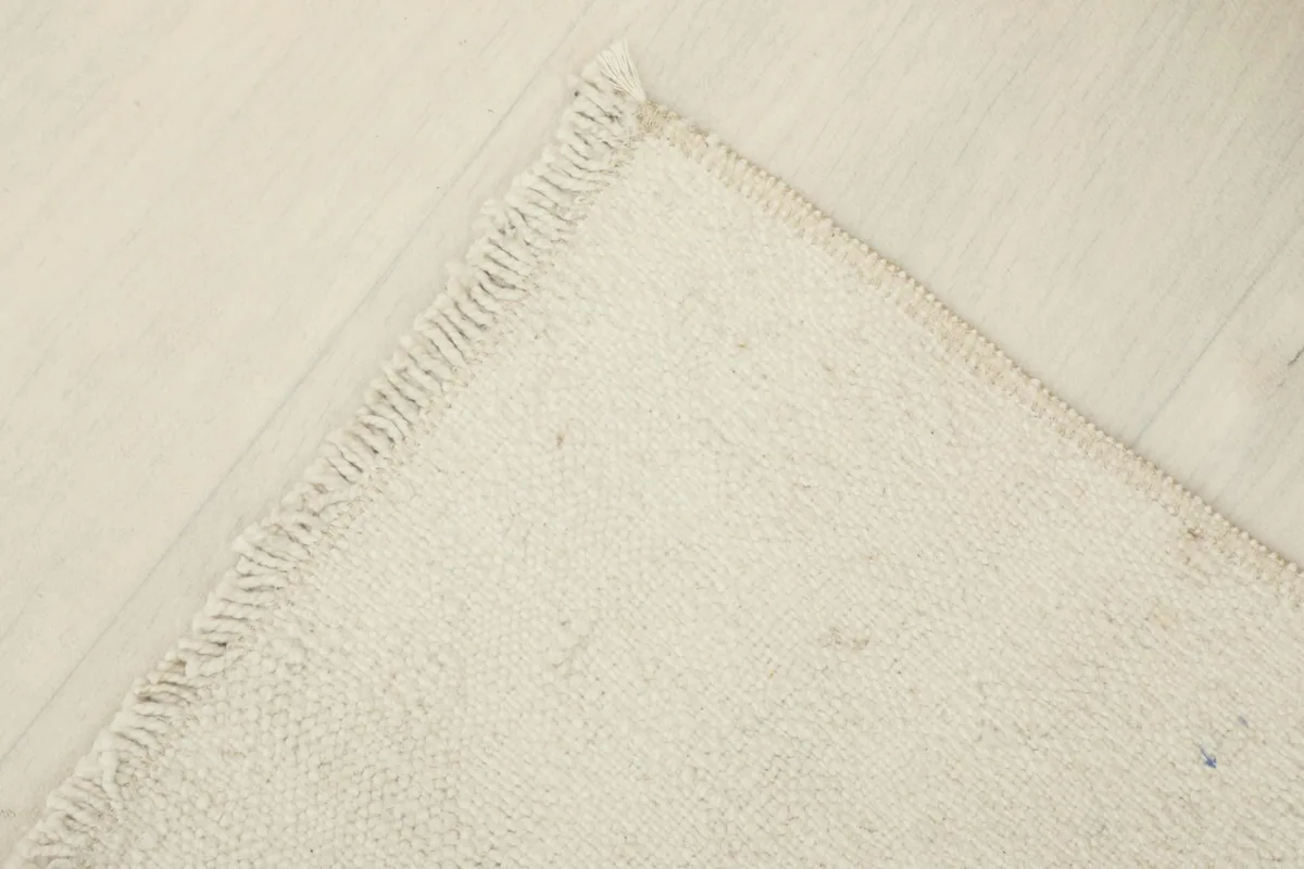 Partial view of the back of the rug, showing the cotton foundation and hand-knotted construction