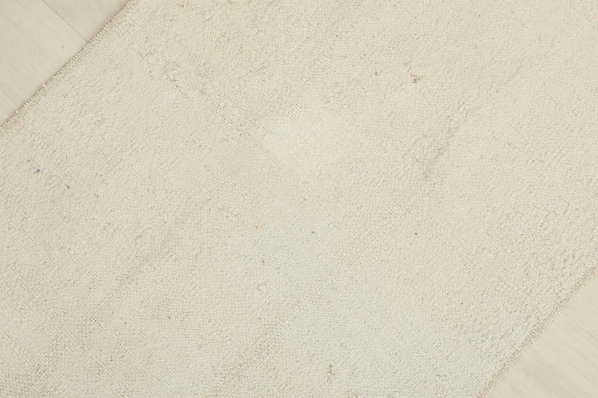 Overhead view showcasing the minimalist design and subtle variations in the ivory wool pile