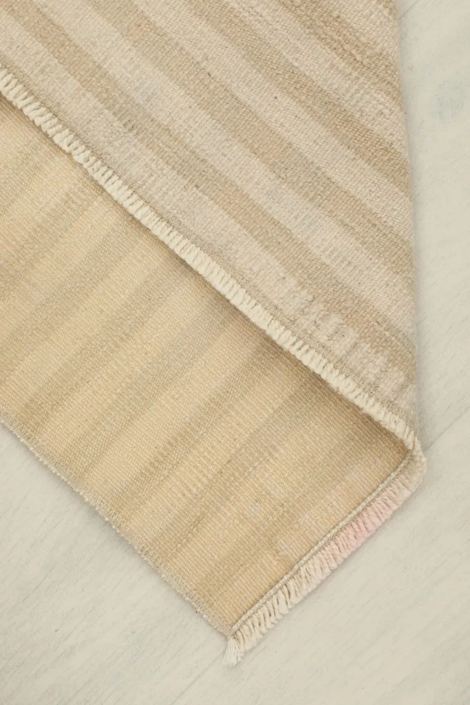 View showing the back of the rug folded over, revealing the cotton foundation and hand-knotted construction.