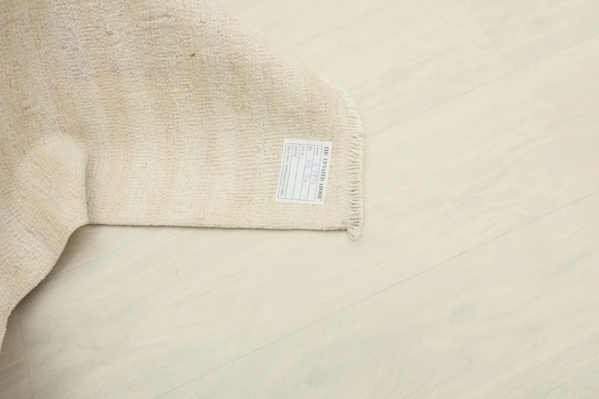 Corner of the rug with a label on the reverse side, showing material and origin