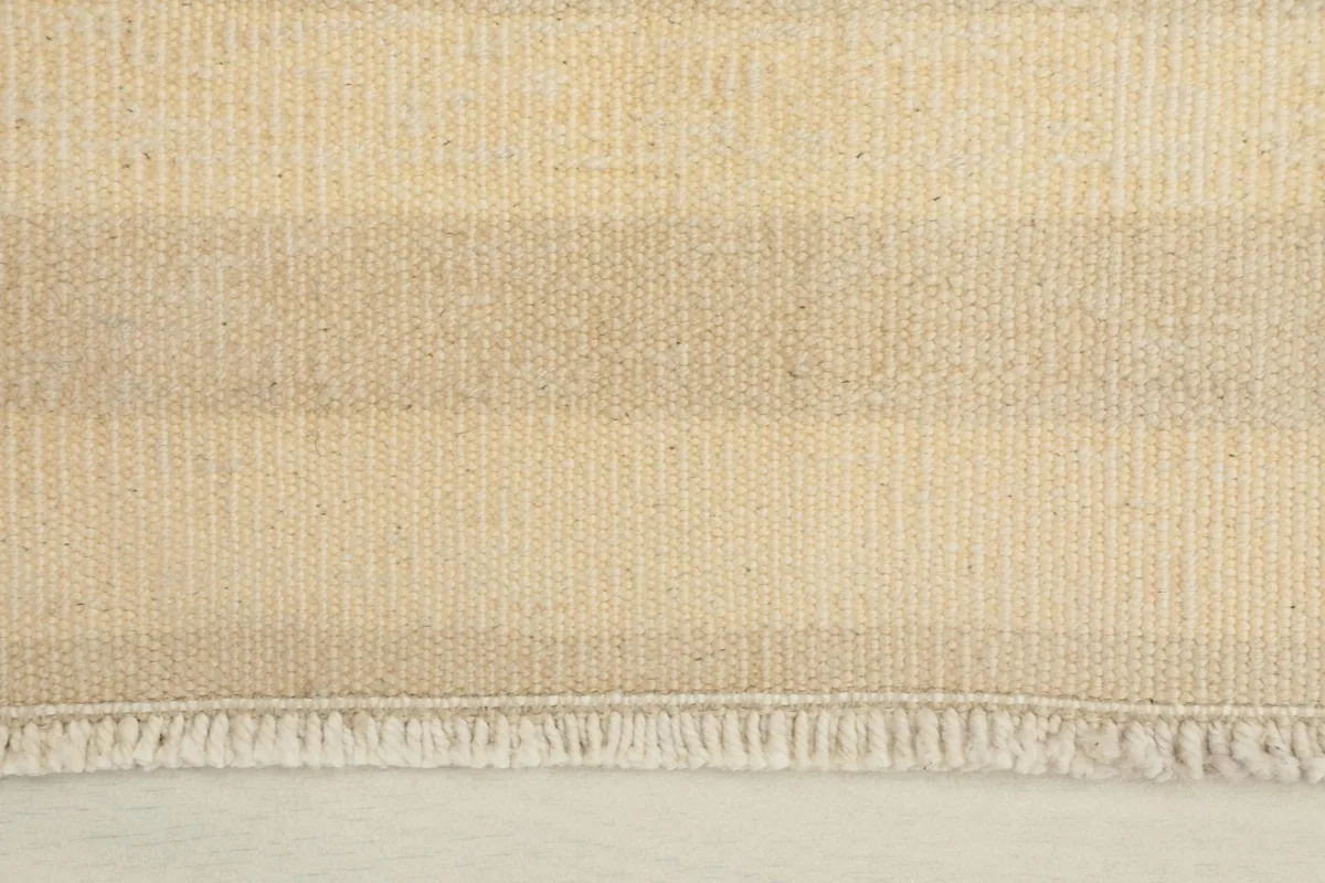 Close-up of the rug's fringe and striped pattern, showing the hand-knotted wool texture.