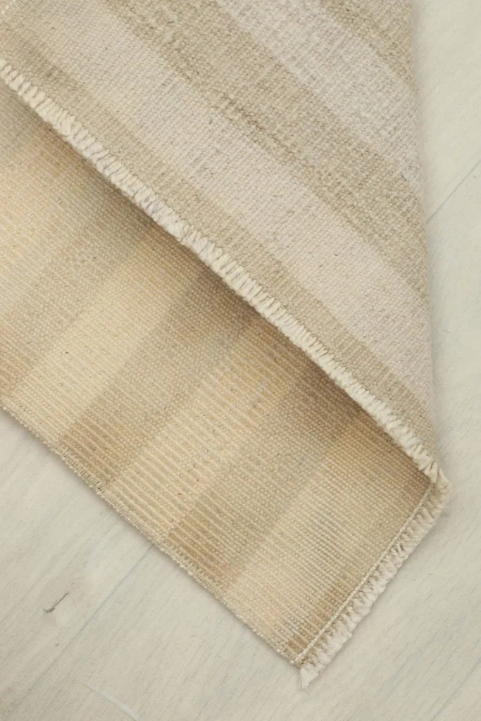 View of the rug folded back to show the underside and the cotton foundation.