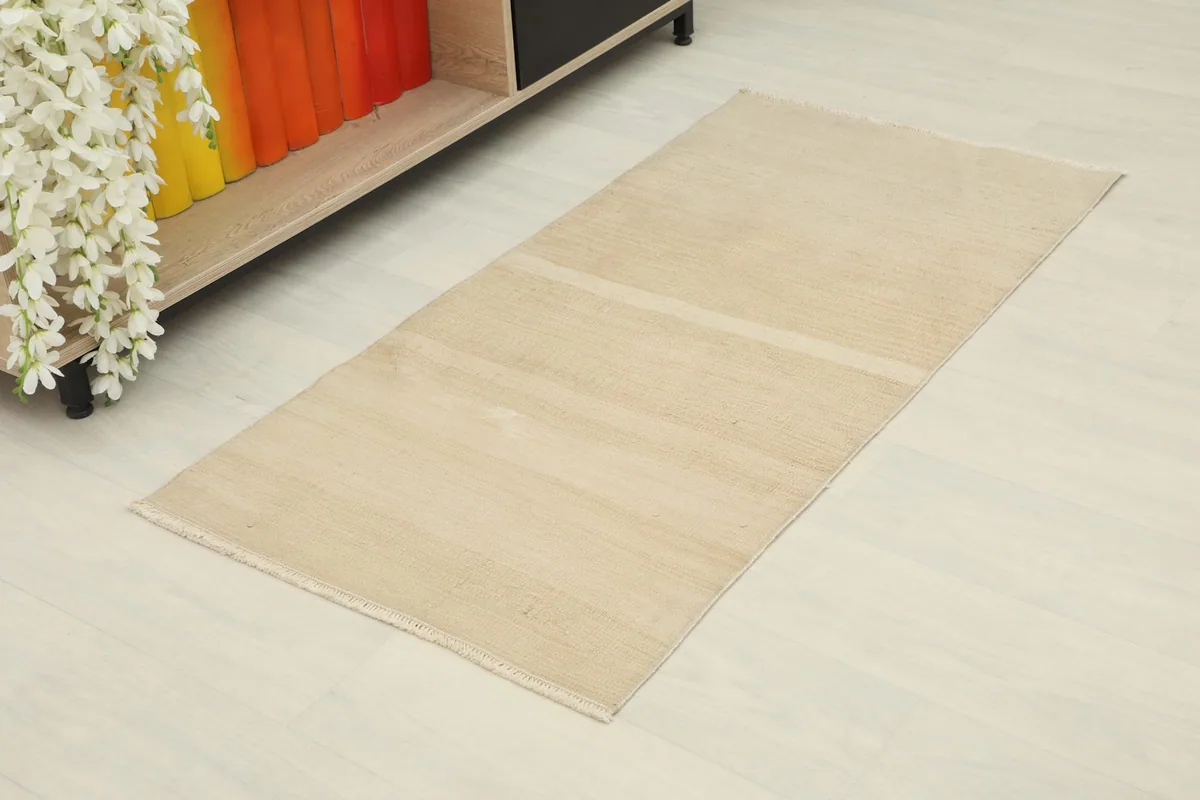 Overhead view of the tan vintage rug in a room setting, showcasing its size and minimalist design.