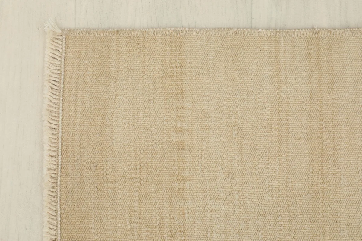 Corner detail of the rug, showing the intact edges and short, neat fringes.
