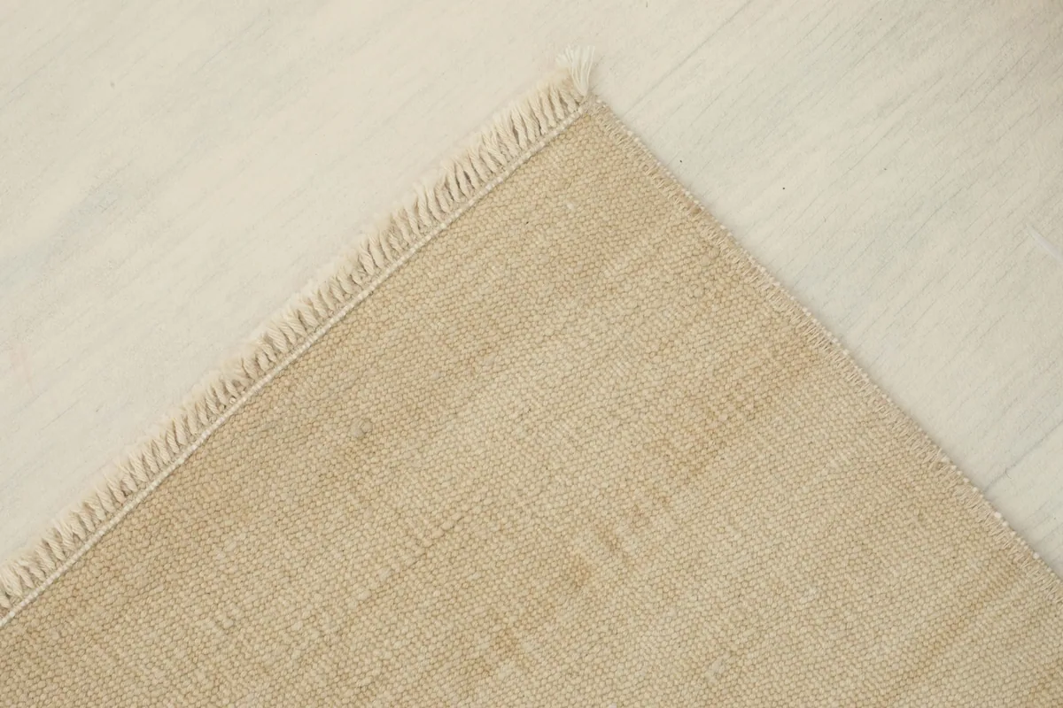 View of the underside of the rug, revealing the cotton foundation and hand-knotted construction.