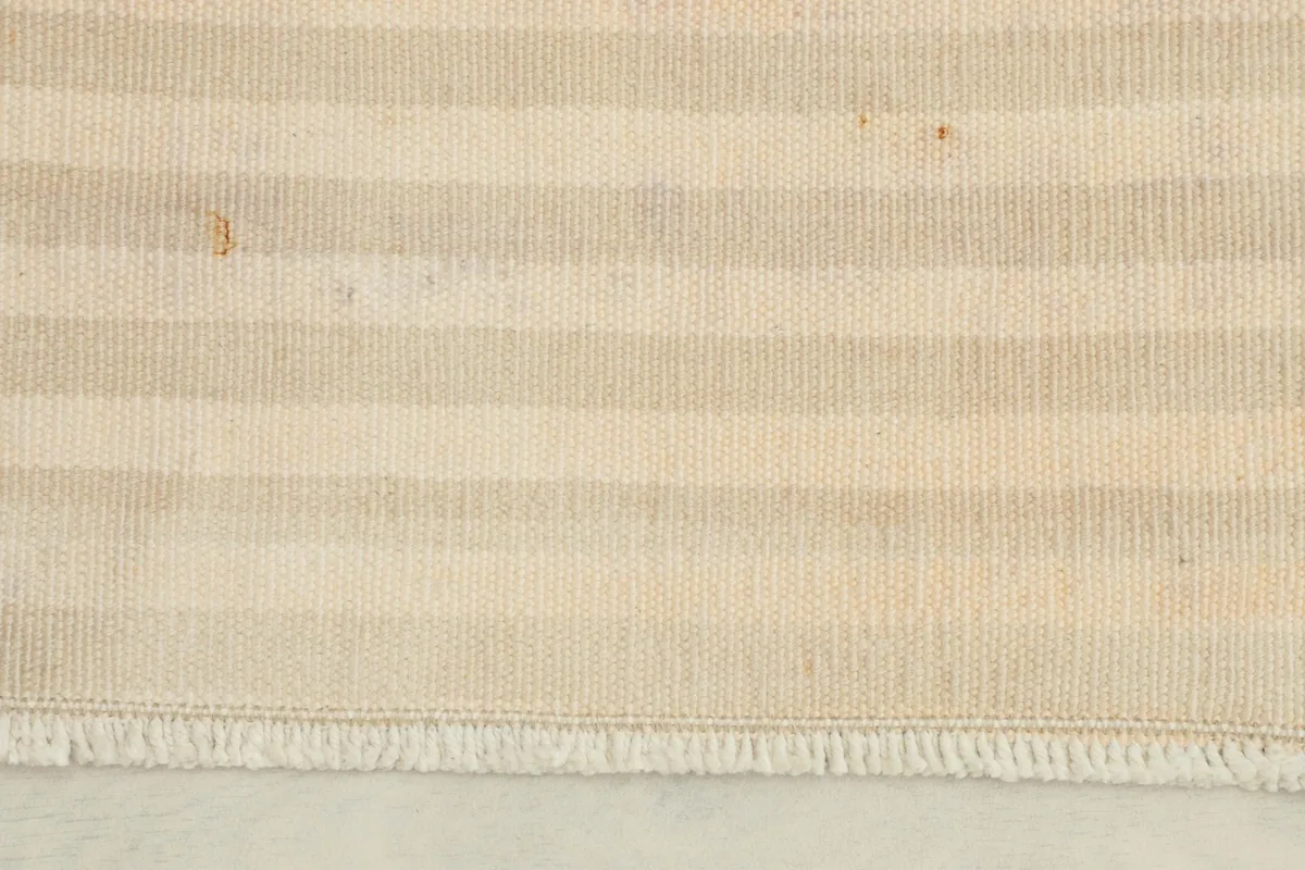 Close-up of the doormat's cream and beige stripes, highlighting the texture and fringe.