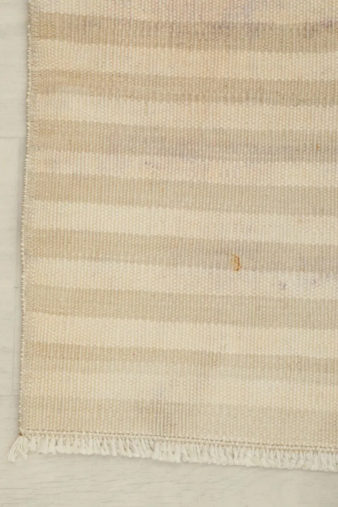 Detail shot of the rug's corner, showing the striped pattern and short fringe.