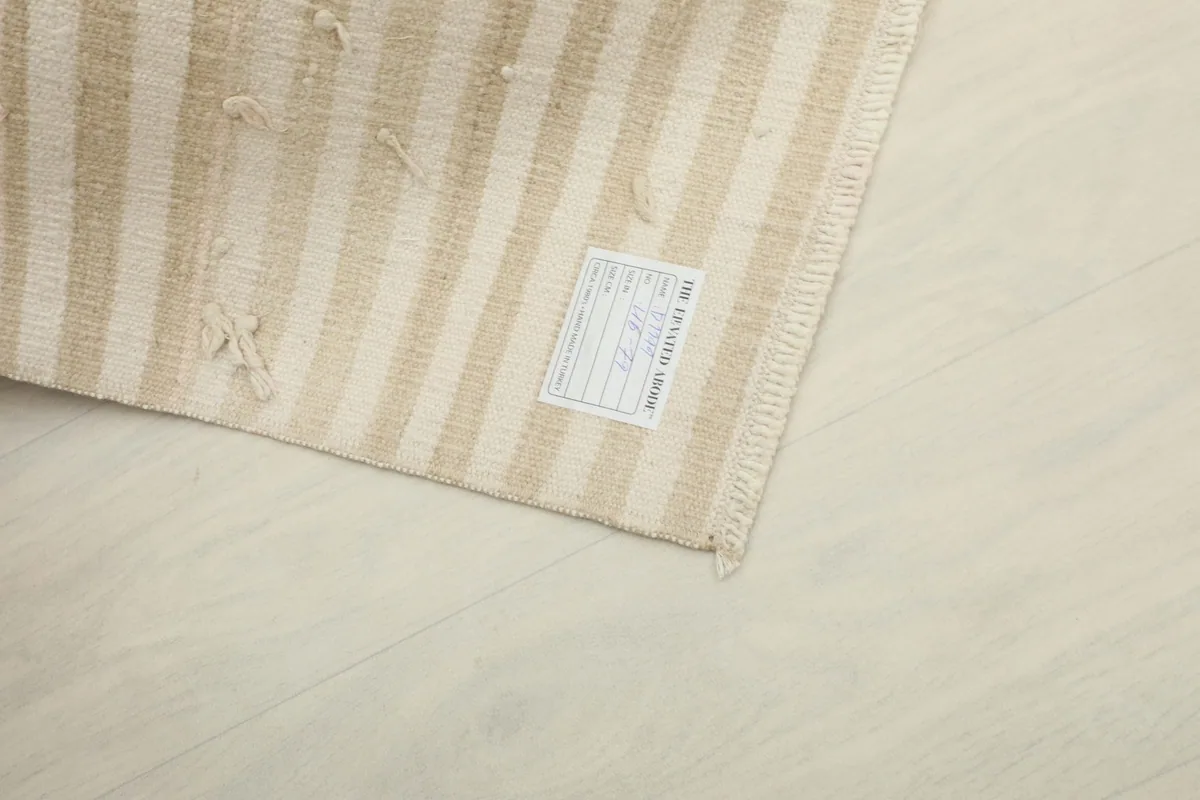 Underside of the rug showing the hand-knotted cotton foundation and a product label.