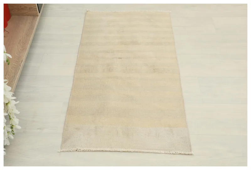 Full overhead view of the beige vintage Anatolian area rug on a white floor.