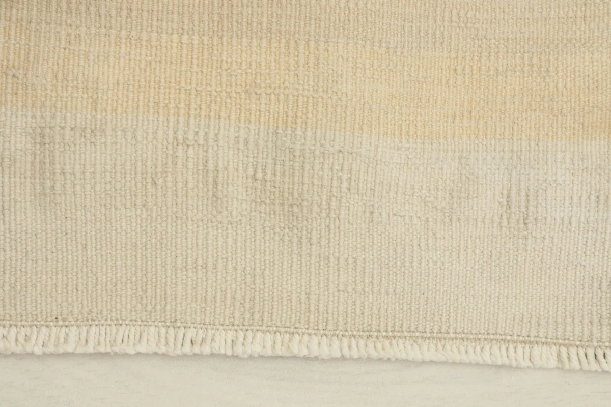 Close-up detail of the rug's short fringe and subtle horizontal stripe texture.