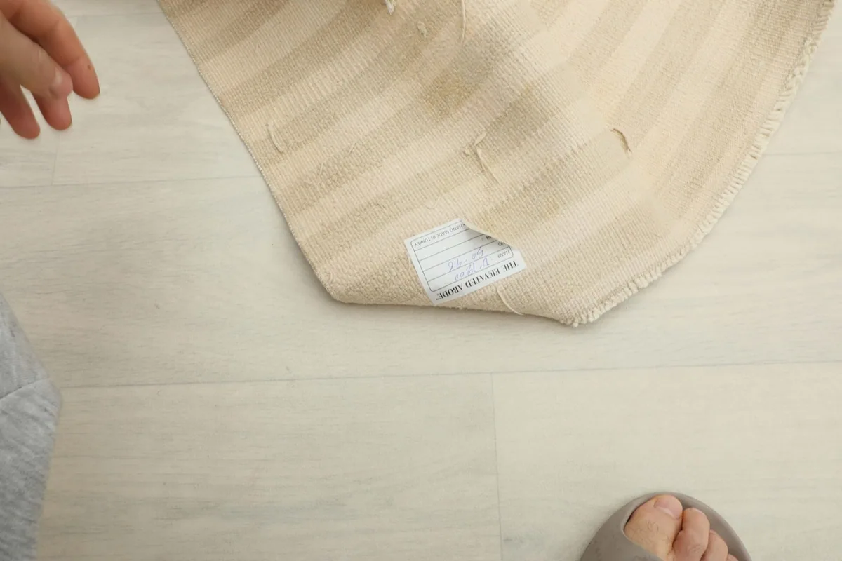 A person's foot next to the rug, indicating its small size and texture.