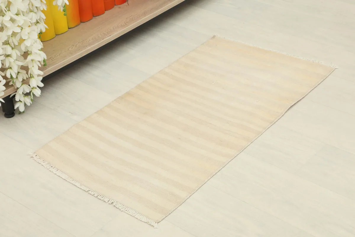 Angled view of the beige striped rug placed on a light floor in a home setting