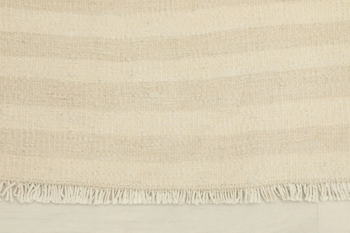Close-up detail of the hand-knotted beige and ivory stripes and fringe
