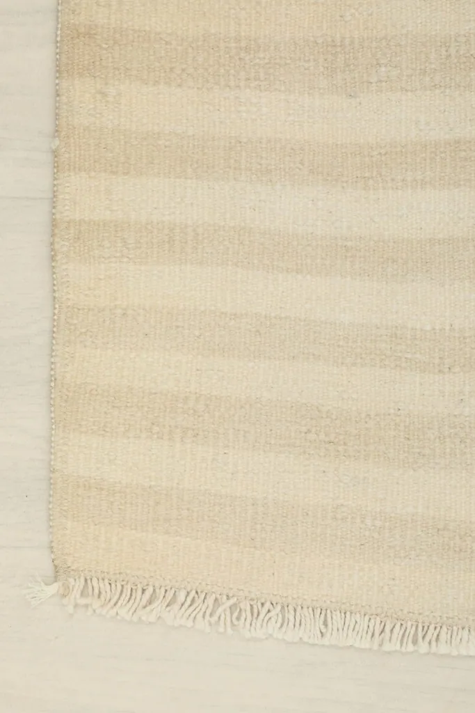 Corner view of the rug, showing the edge and a short fringe