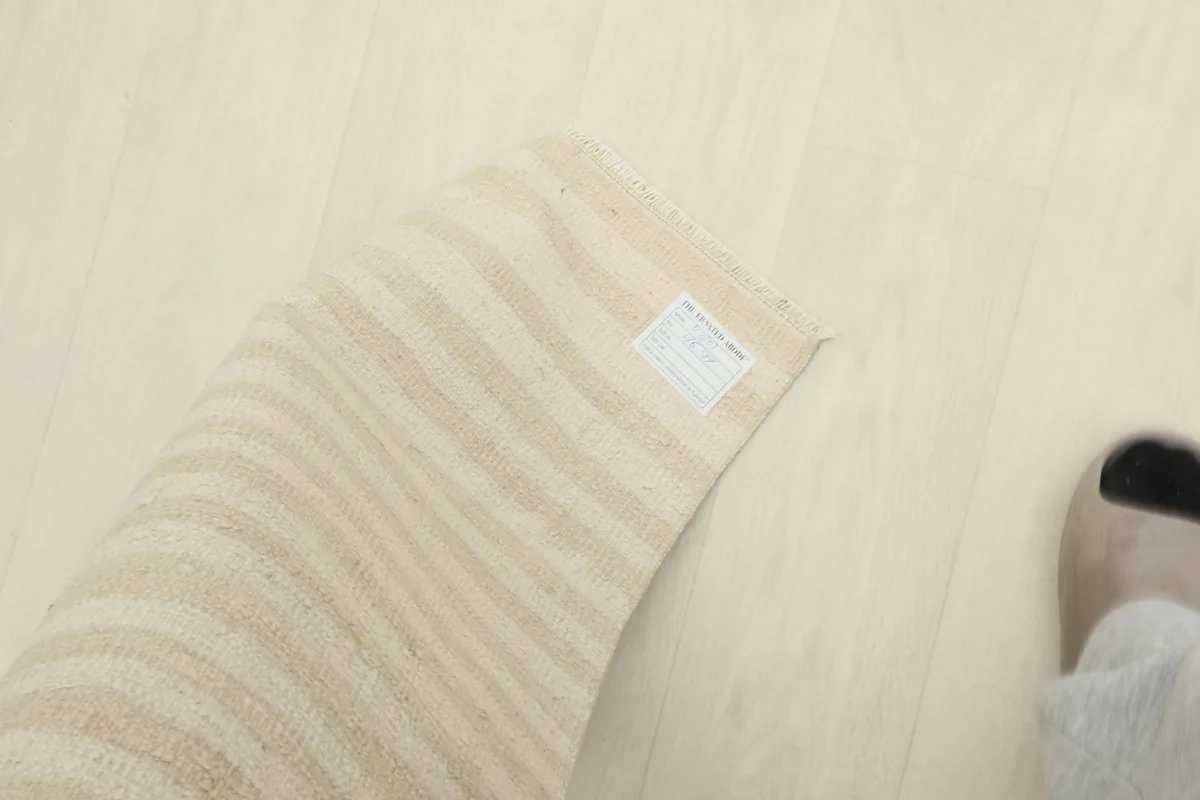 Corner of the rug with a tag, next to a foot for scale