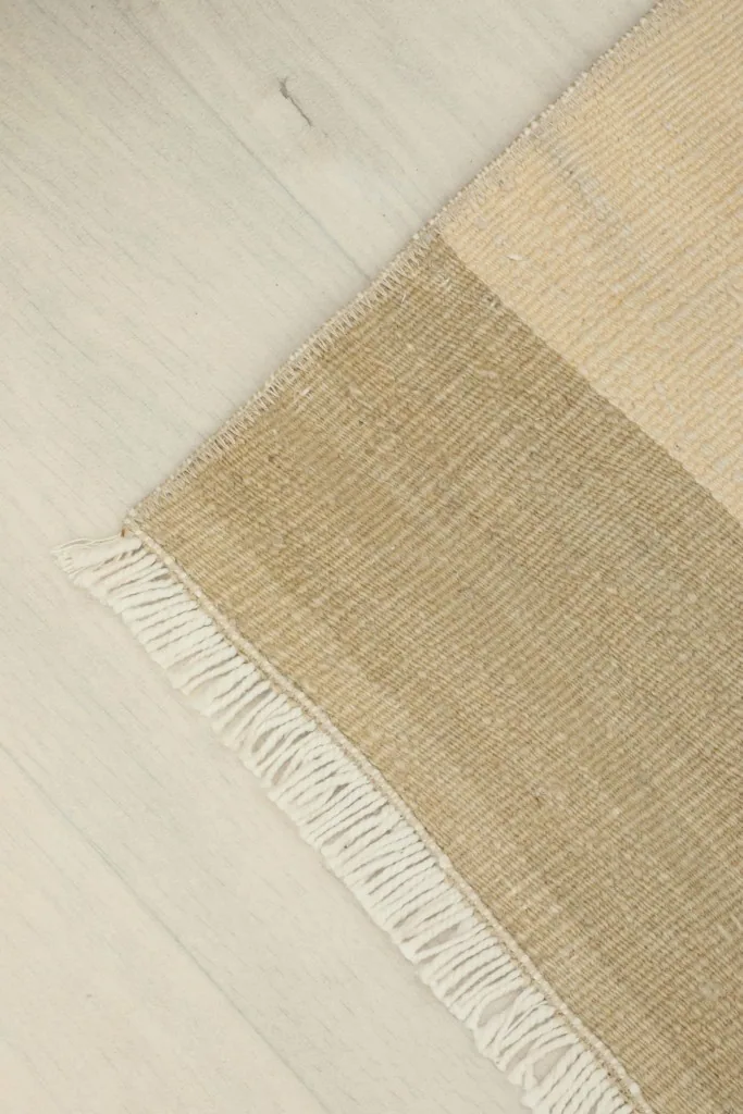 Corner view of the rug, showing the side binding and the transition from the rug to the floor.