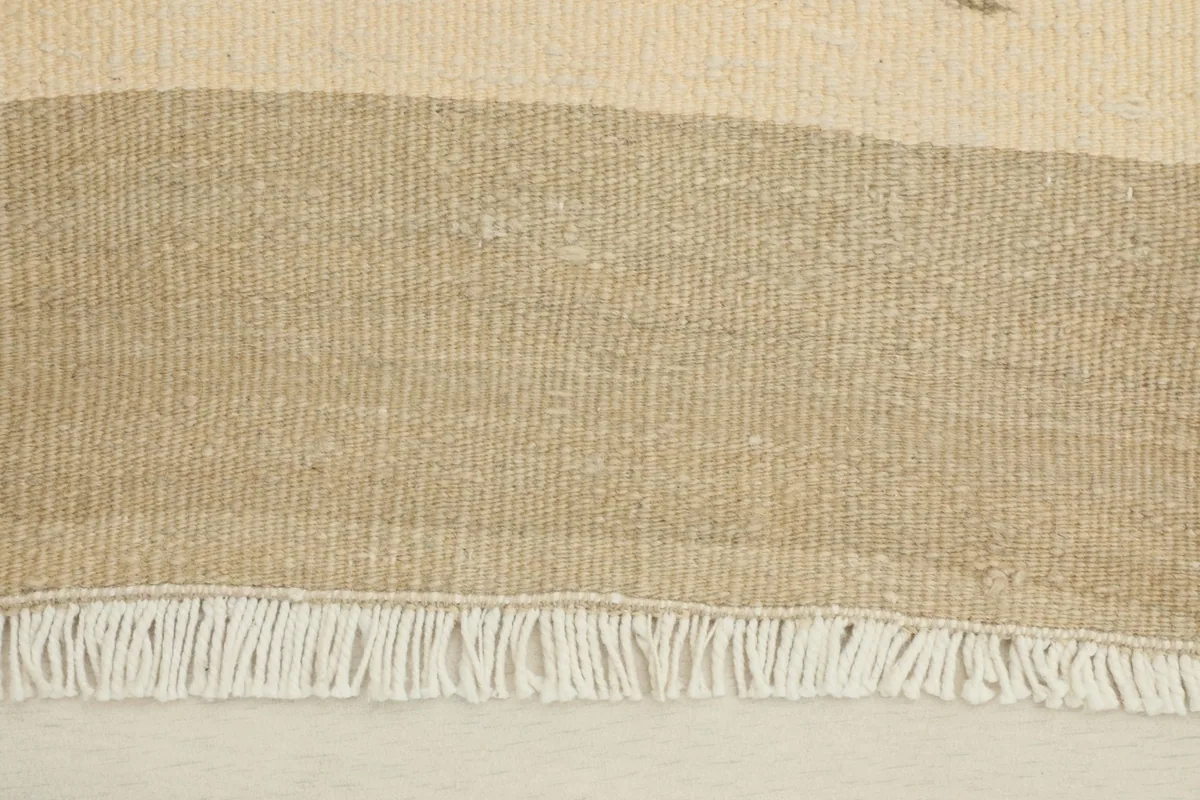 Close-up detail of the tan stripe and ivory field, showing the hand-knotted wool pile and fringe.