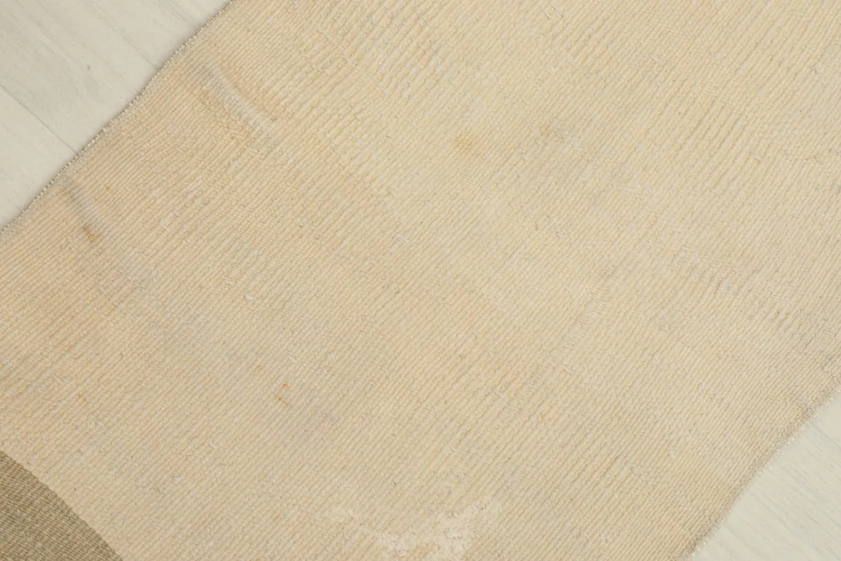 Detailed view of the ivory section of the rug, highlighting the texture and subtle variations in the vintage wool.