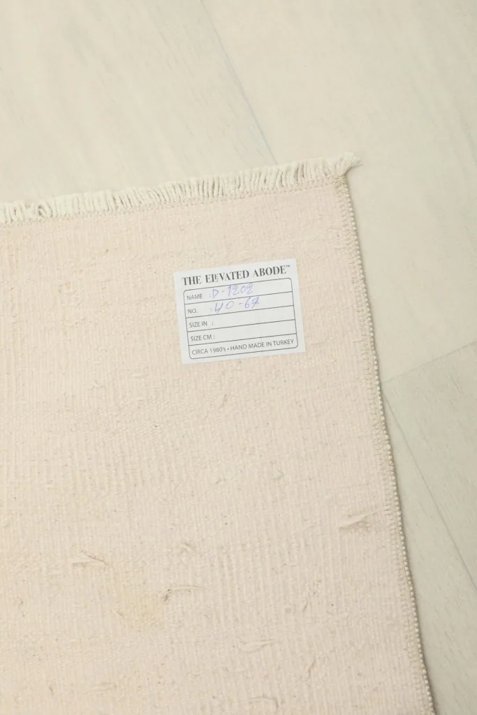 Close-up of the back of the rug with a tag, displaying the tight hand-knotted cotton foundation.