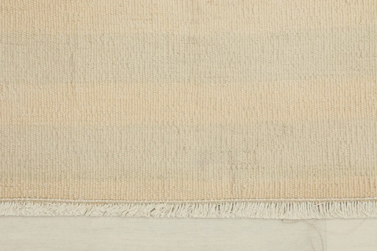 Close-up detail of the doormat's low wool pile and short fringes at one end.