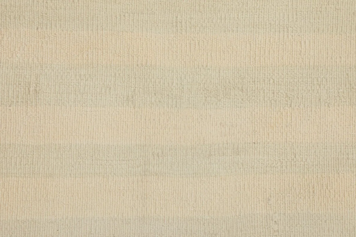 Overhead close-up of the ivory wool pile, showing the hand-knotted texture and gentle striping.