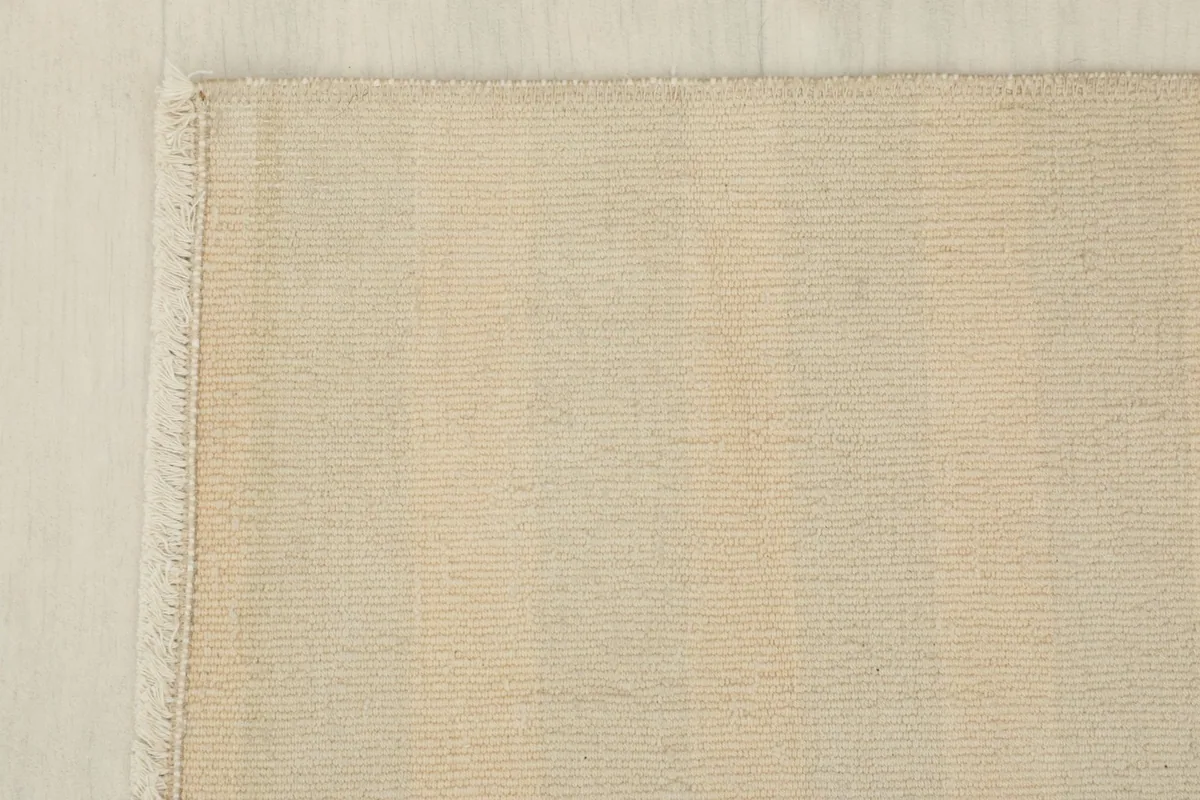Detail of the rug's corner, showing the edge finish and short fringe.