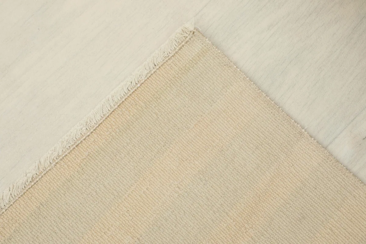 Underside view of the rug, revealing the cotton foundation and knotting structure.