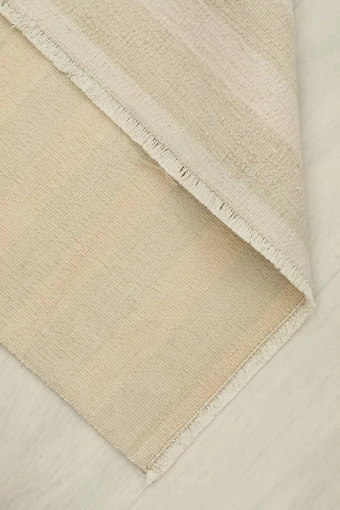 Folded corner of the rug, showing the flexibility and thickness of the wool pile and cotton back.