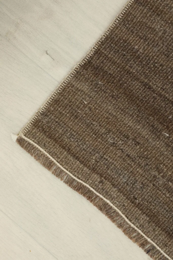 Corner detail of the brown doormat, highlighting the tight weave and finished edge.