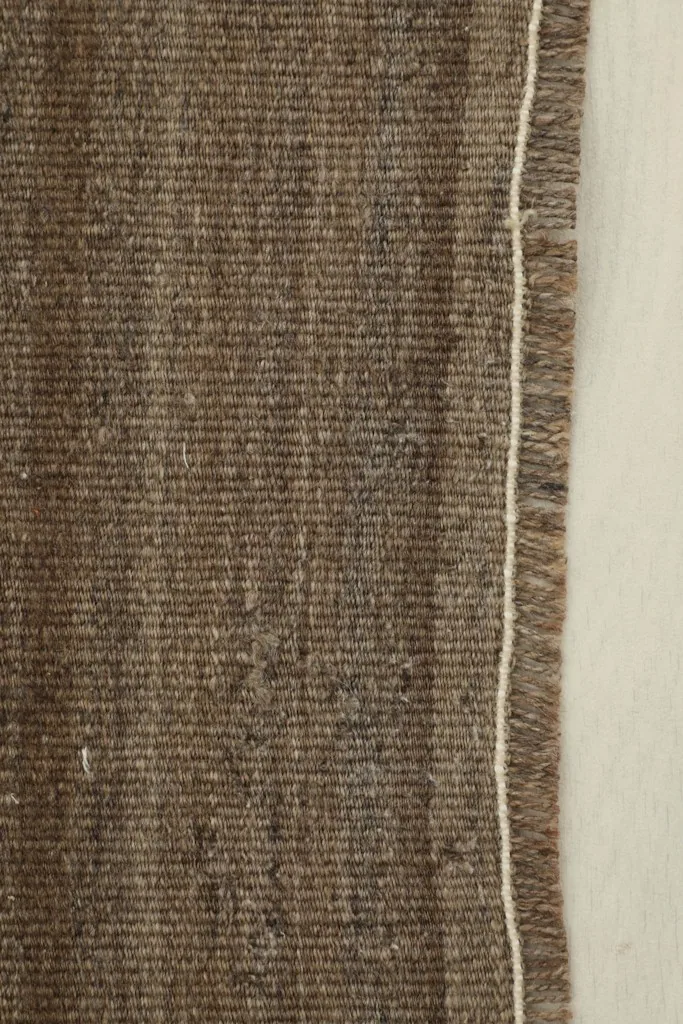 Side detail of the brown doormat, showing the woven edge and the short fringe.