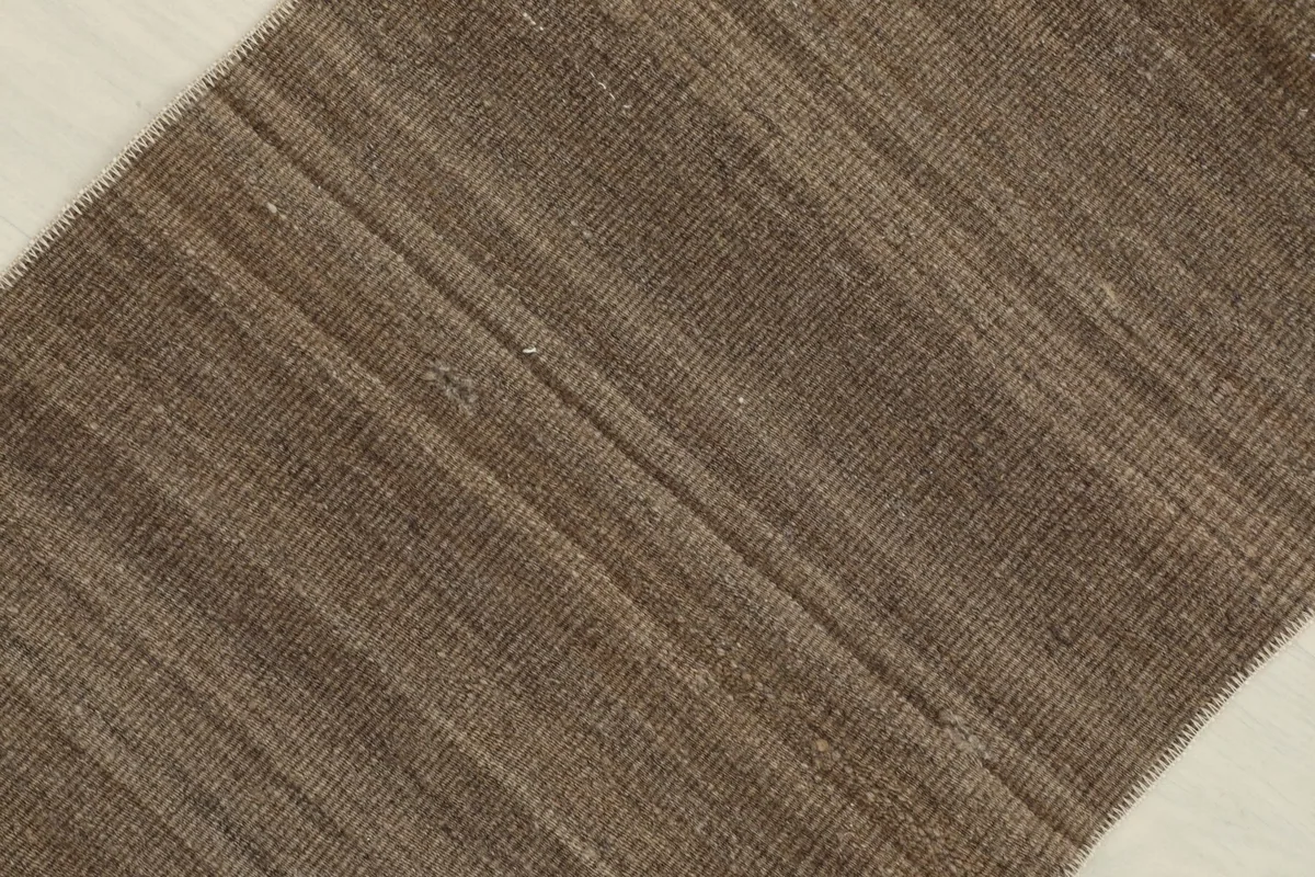 Angled close-up of the brown doormat's surface, highlighting the subtle color shifts within the stripes.