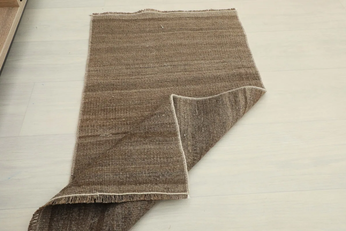 Overhead view of the brown doormat with one end folded, showcasing its flexibility and natural variations.