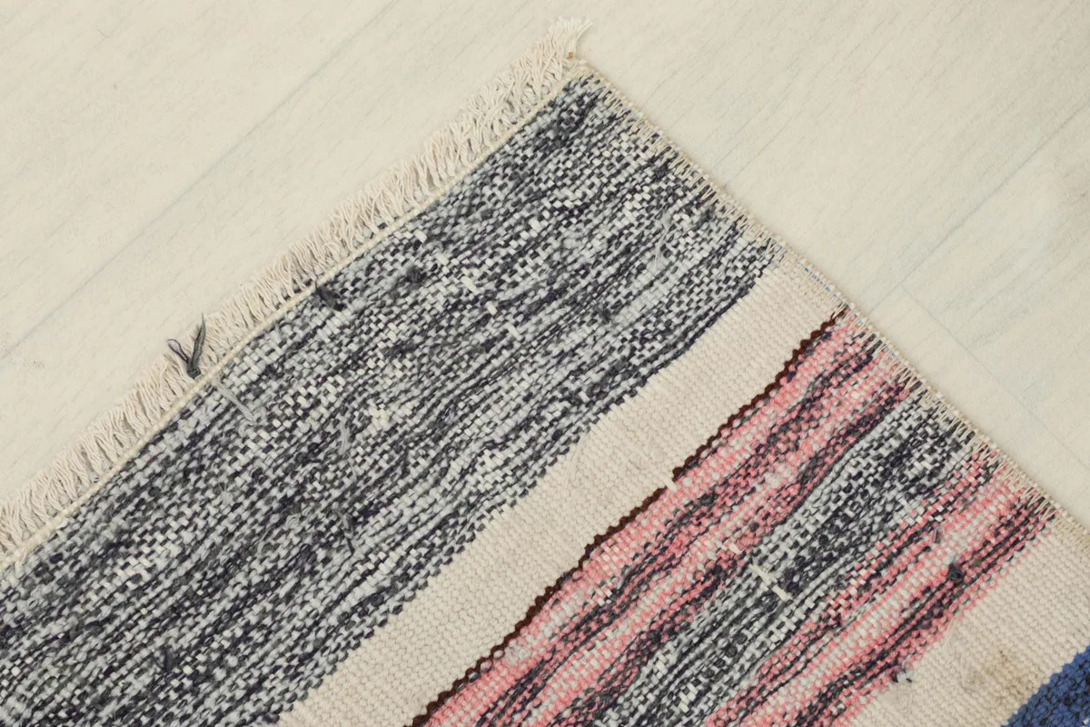 Angled close-up of the rug's corner, showing the varied colors and a small fringe.