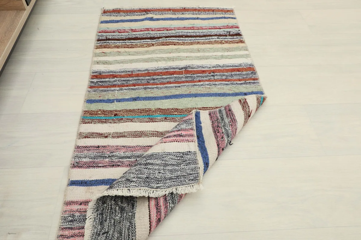The multicolor striped rug partially rolled up on one end, displaying its full pattern.