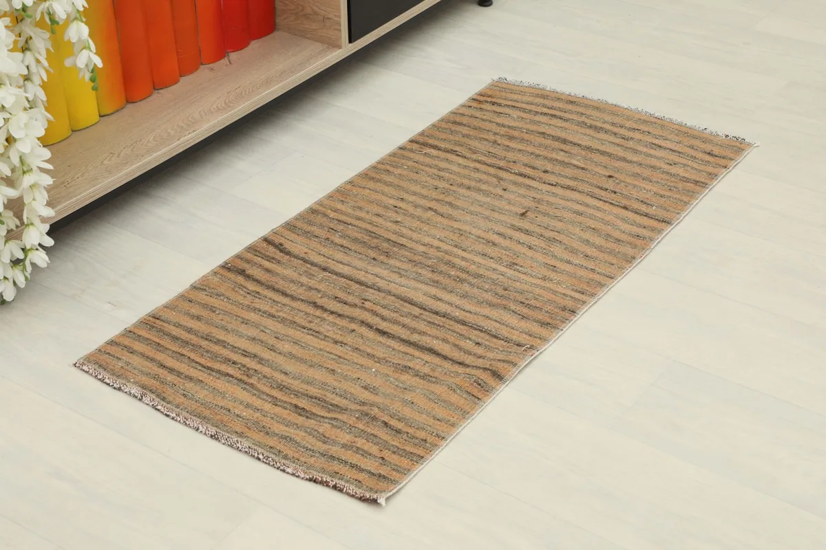 Angled view of the striped Anatolian rug, showing its length and texture on a light floor.