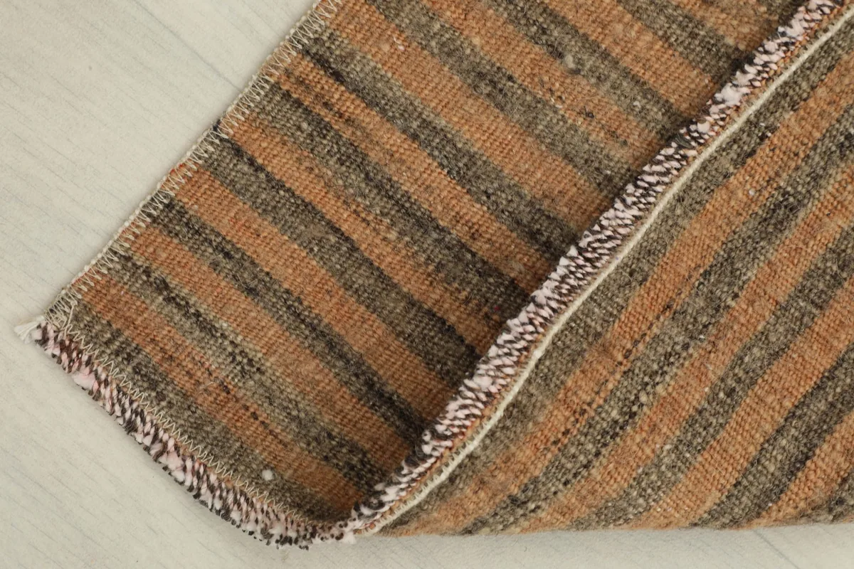 Rug corner folded back, revealing the reverse side and the cotton foundation.