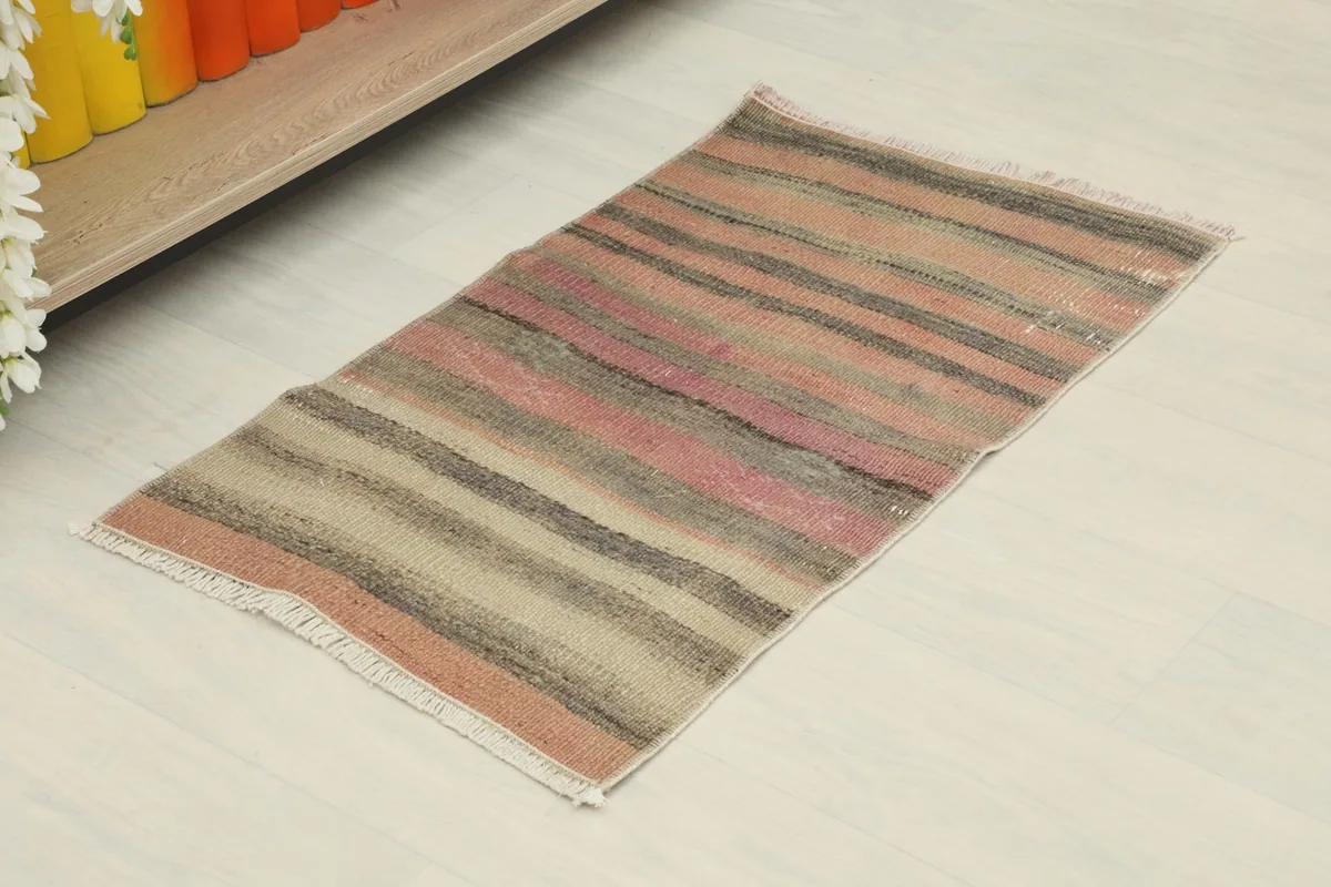 Slightly angled overhead view of the striped vintage doormat, showing its full length and colors.