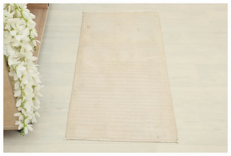 Full top view of the 1'6" x 3'2" beige striped vintage Anatolian rug on a light floor.