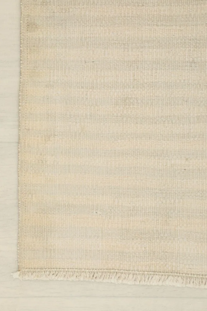 View of the rug's edge, showcasing the neat finish and the short, natural fringe.