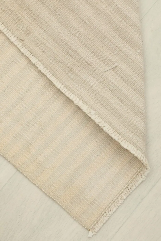 Rug corner folded back, revealing the cotton foundation and the reverse side of the hand-knotted pile.